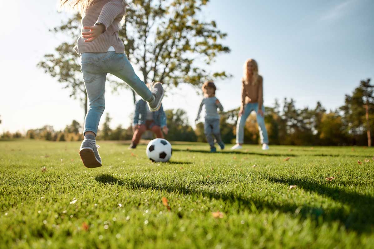 Natur in der Stadt – Kinder spielen Fußball auf einer Wiese.