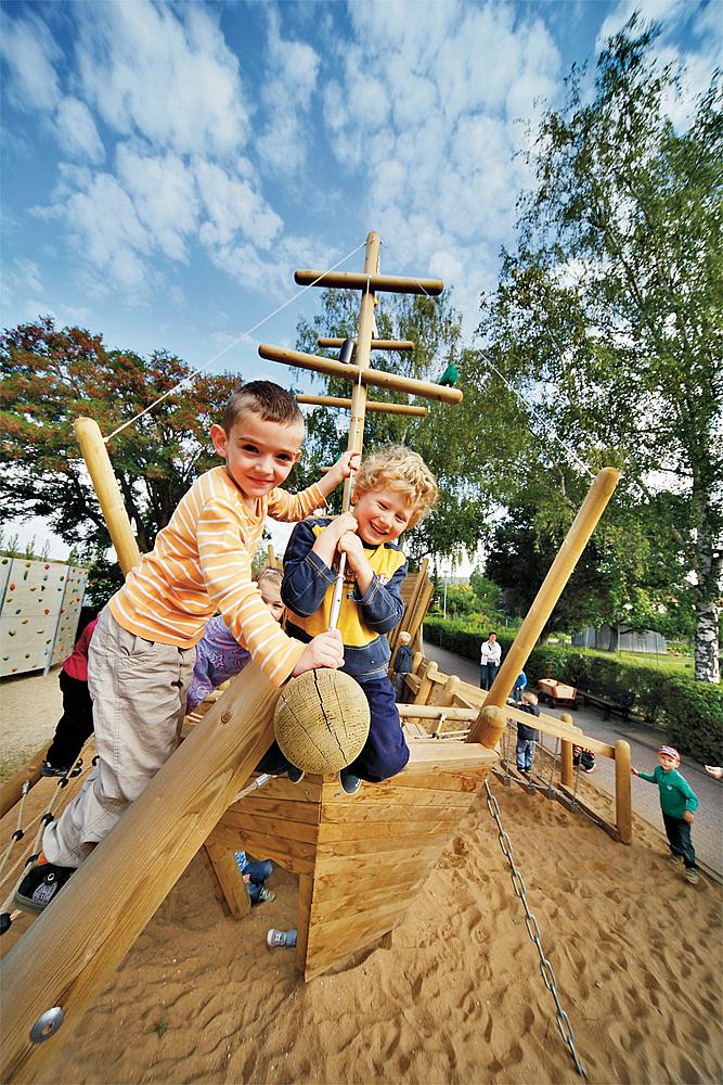 Themenspielplatz – Zwei kleine Jungen sitzen auf der Spitze des Spielschiffes Santa Maria von eibe.