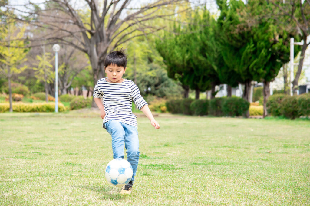 Bewegung hilft, Stress bei Kindern abzubauen – ein Junge spielt Fußball auf einer grünen Wiese.