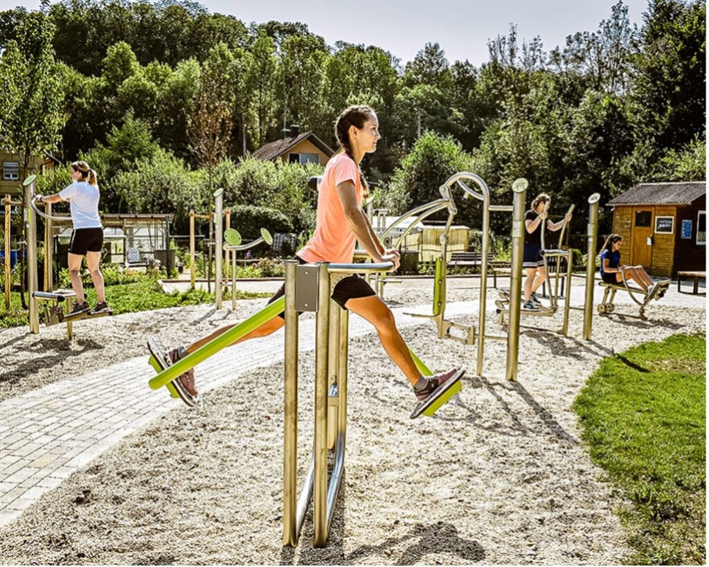 Outdoor-Fitness – eine junge Frau trainiert an einer Bewegungsstation ihre Beine.