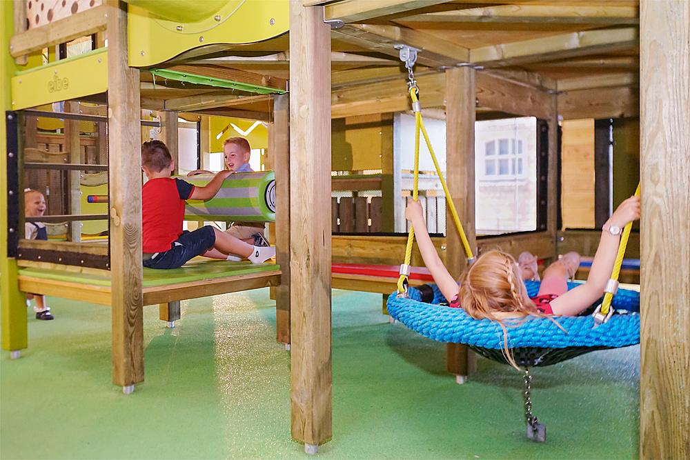 Indoor-Spielplatz bauen – Kinder auf einem Indoor-Spielplatz mit Nestschaukel von eibe.