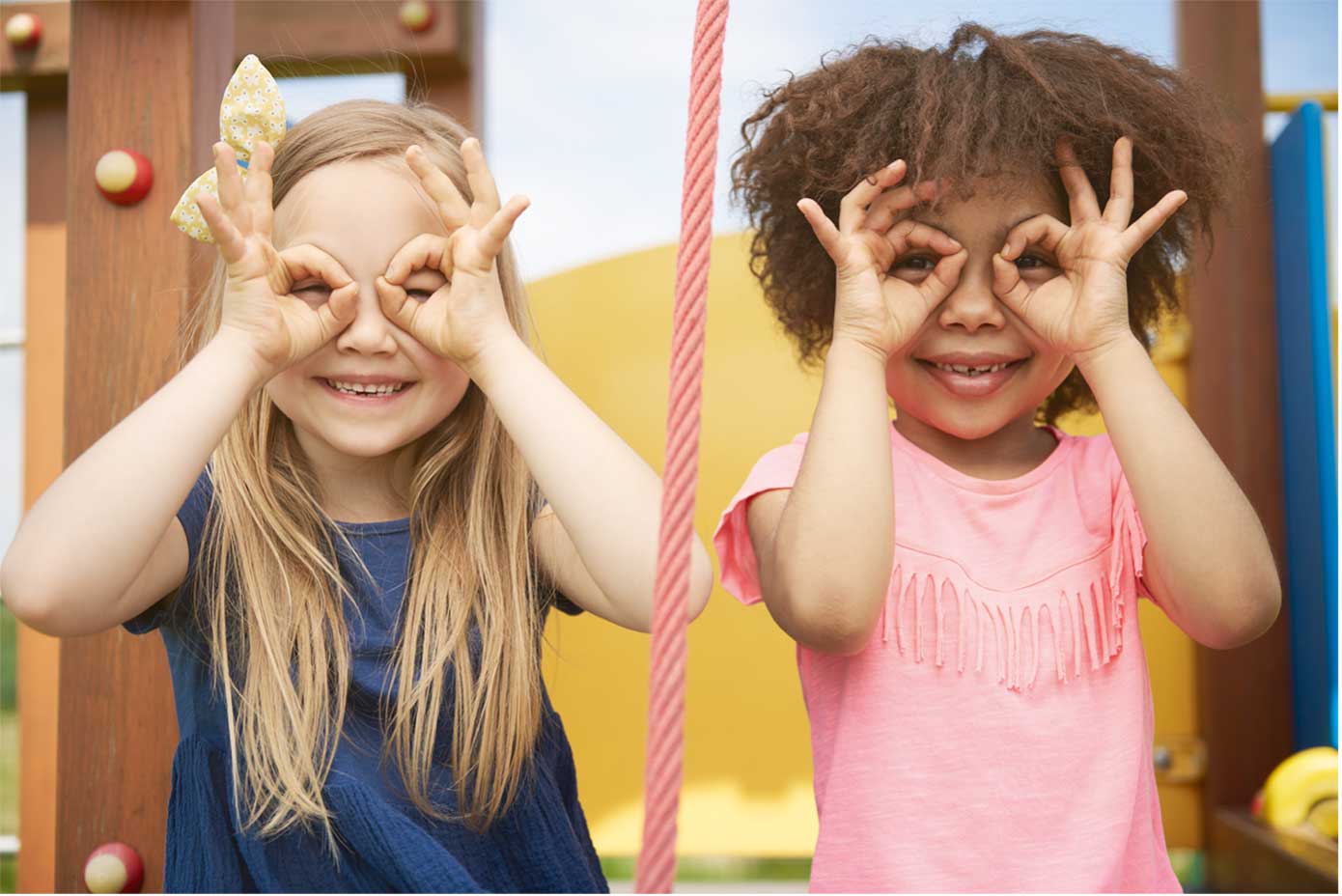 WHO Bewegungsempfehlung für Kinder – Zwei lachende Mädchen, die sich die Hände zur Brille geformt vors Gesicht halten.