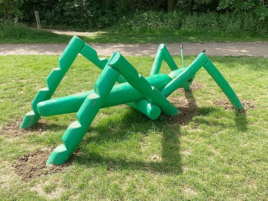 Spielplatzgestaltung – Ein Klettergerät in Form einer großen, grünen Heuschrecke.