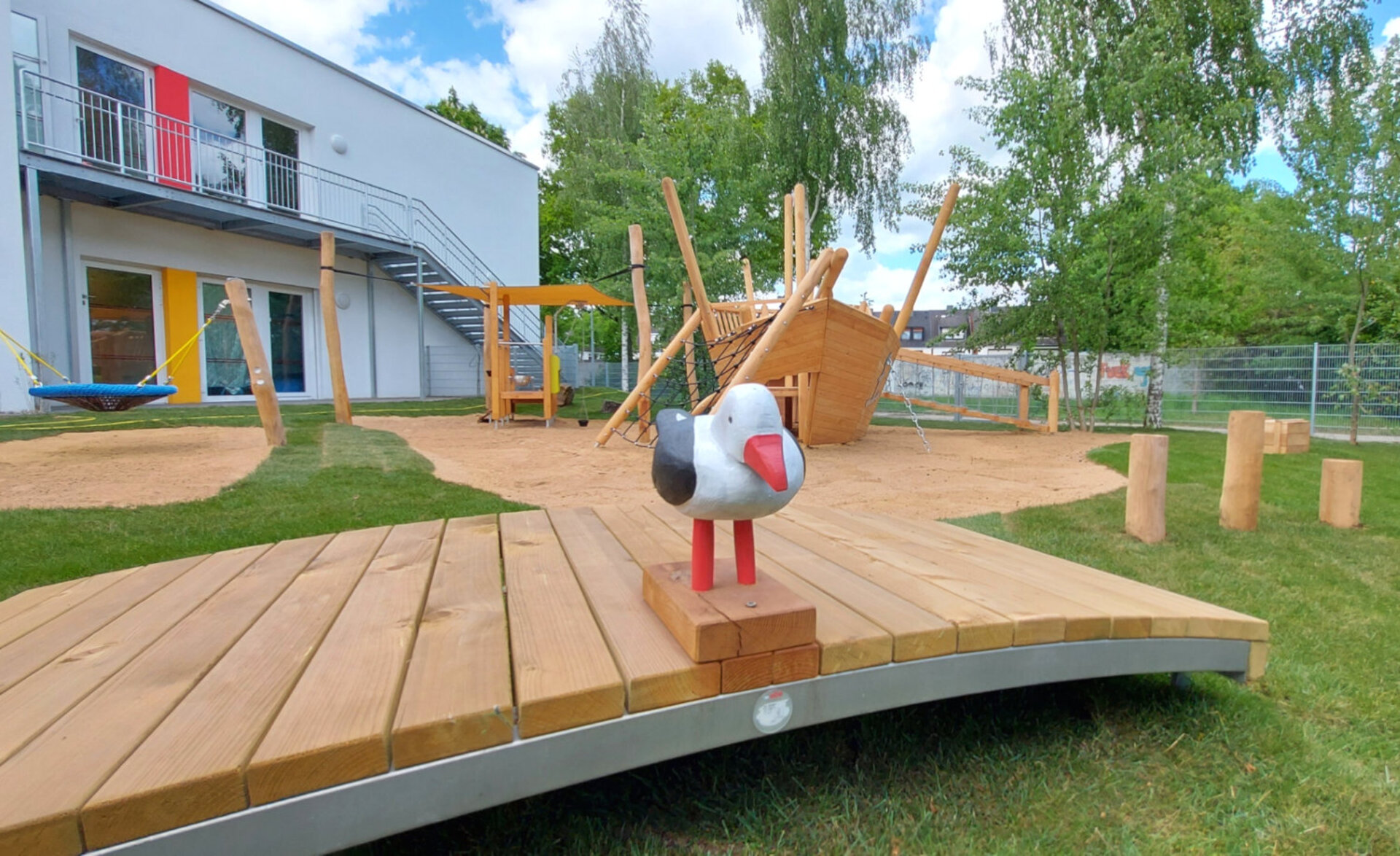 Spielplatzgestaltung – Eine Möwe aus Holz, die auf der Brücke einer Spielanlage sitzt.