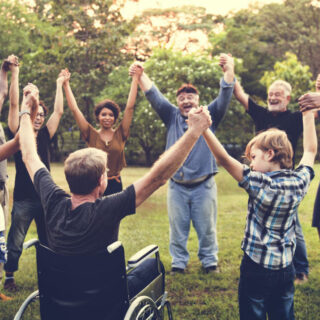 Inklusive Spiele – Behinderte und nicht behinderte Kinder und Erwachsene bilden einen Kreis und halten sich an den Händen.
