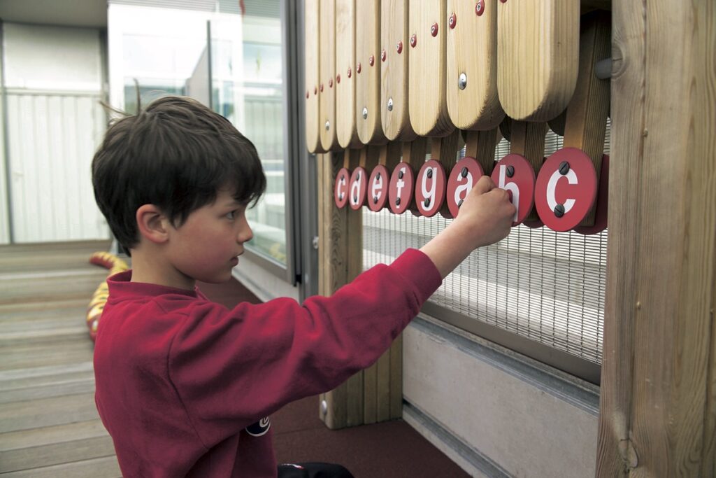 Wahrnehmung fördern – Ein Junge spielt an einem Hängeklavier aus Holz.