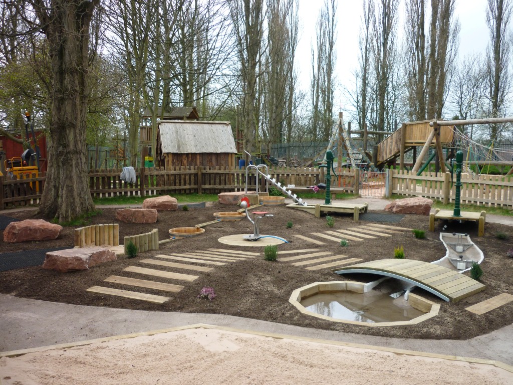 Ein Wasserspielplatz von eibe mit Becken, Wegen und Zäunen aus Holz.